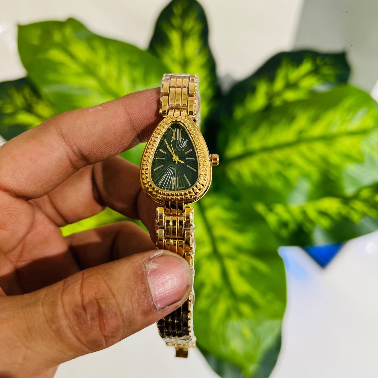 Teardrop-shaped analog timepiece featuring a green sunburst dial with Roman numerals at the 12 and 6 positions